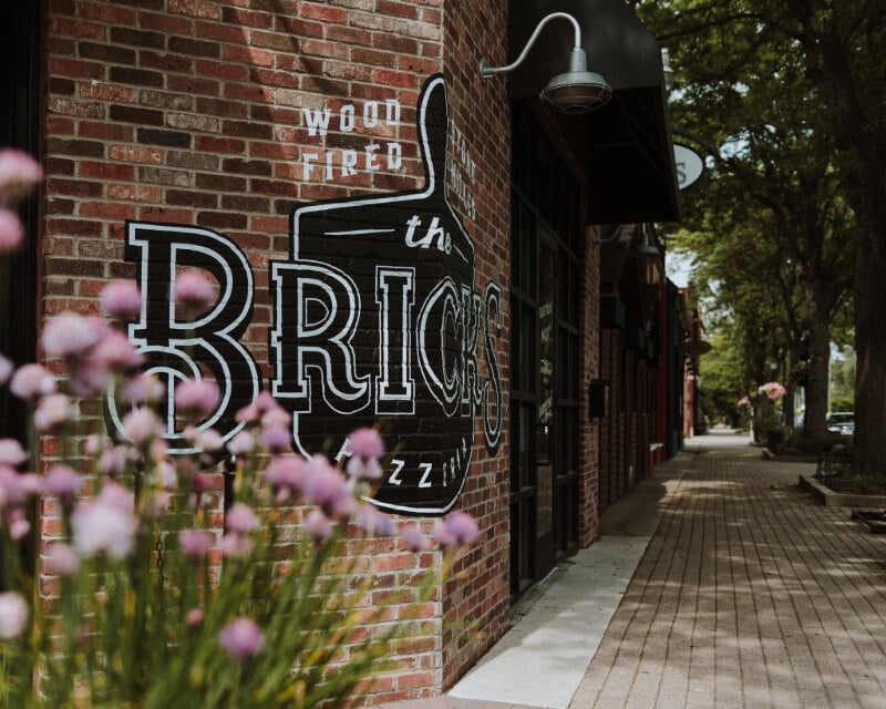 Painted brick facade and entrance sign featured on about The Bricks Pizzeria page