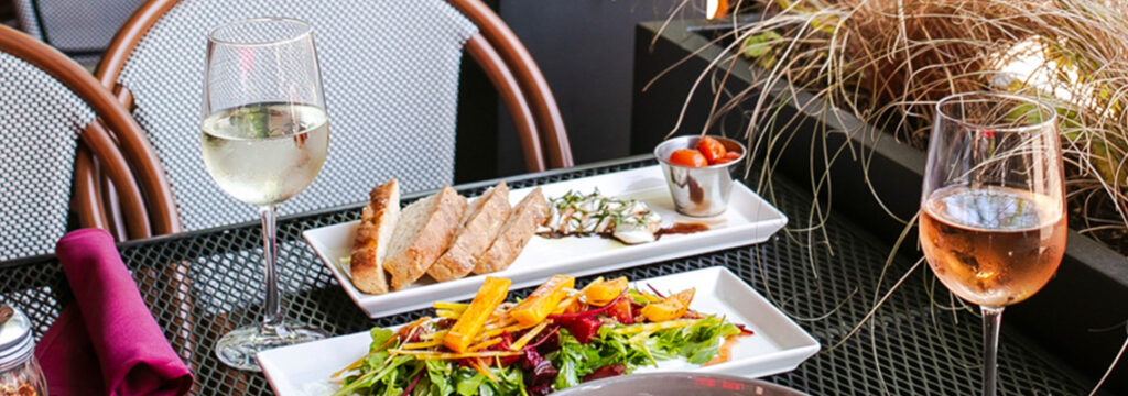 Fresh artisanal bread, seasonal beet salad, and wine glasses on a patio table from our food blog